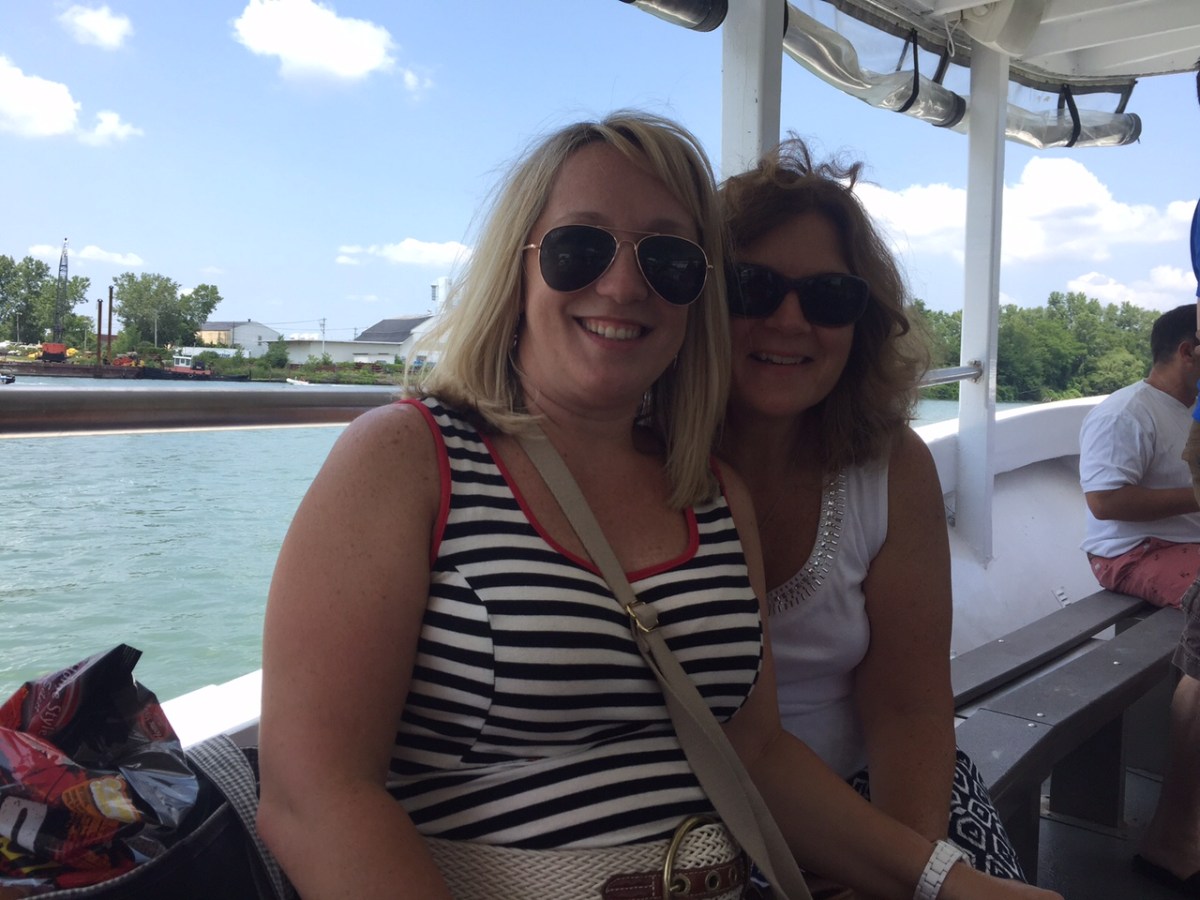 a woman in sunglasses sitting in a boat on a body of water