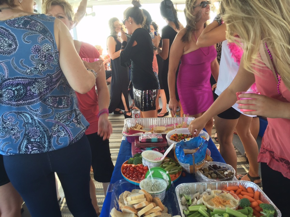 a group of people standing on top of a cutting board with a cake