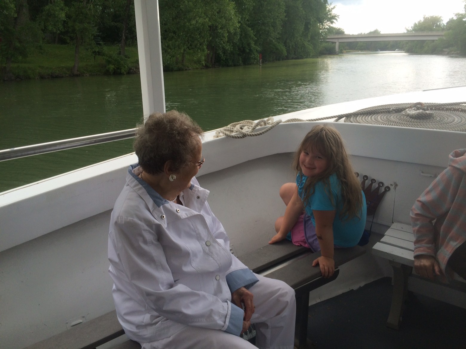 a little girl sitting on a bench next to a body of water